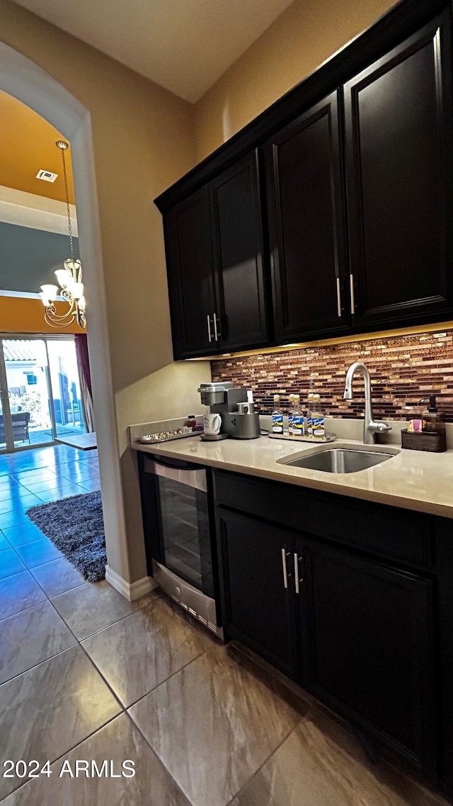 kitchen with tasteful backsplash, wine cooler, sink, and a notable chandelier