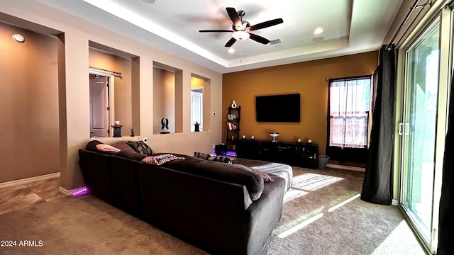 living room featuring a tray ceiling, ceiling fan, and carpet