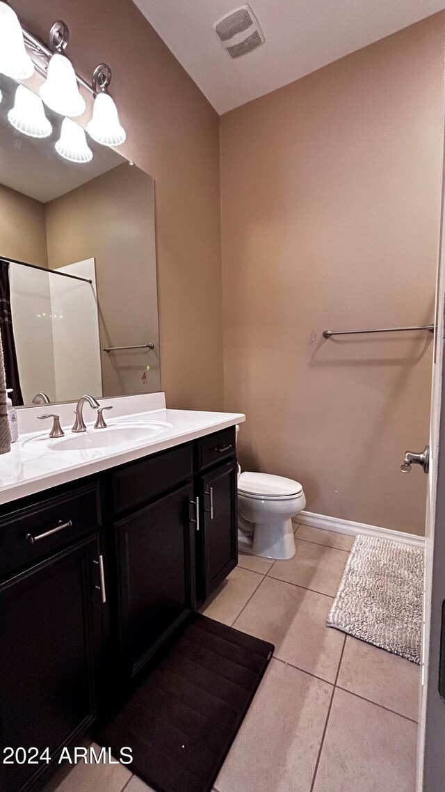 bathroom with toilet, vanity, tile patterned floors, and walk in shower