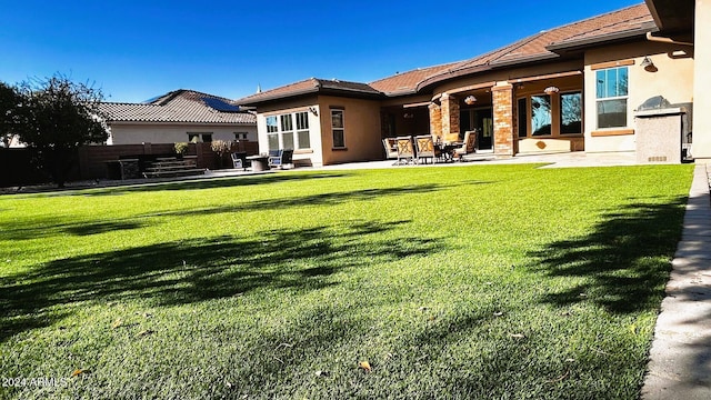 back of property featuring a patio area and a yard