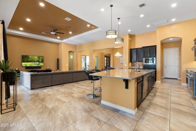 2285 E Mead Dr, Gilbert, AZ 85298 - kitchen with arched walkways, open floor plan, a sink, a kitchen bar, and recessed lighting