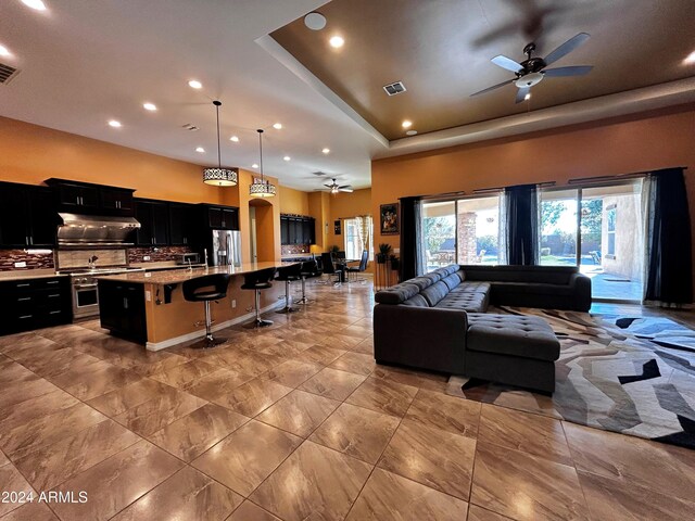 living room with a raised ceiling and ceiling fan