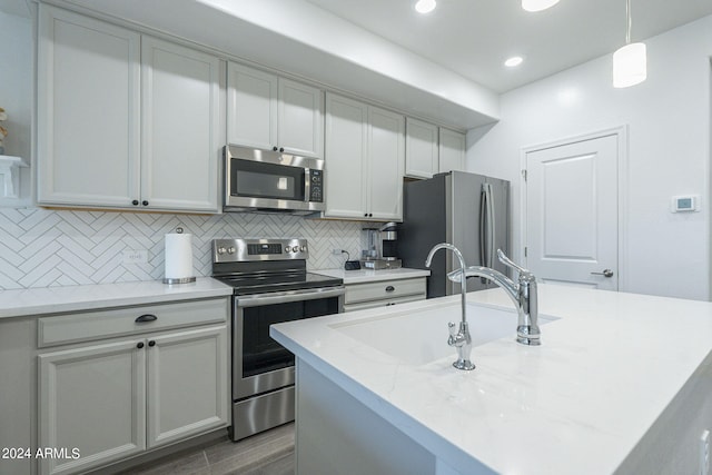 kitchen featuring pendant lighting, an island with sink, stainless steel appliances, and sink