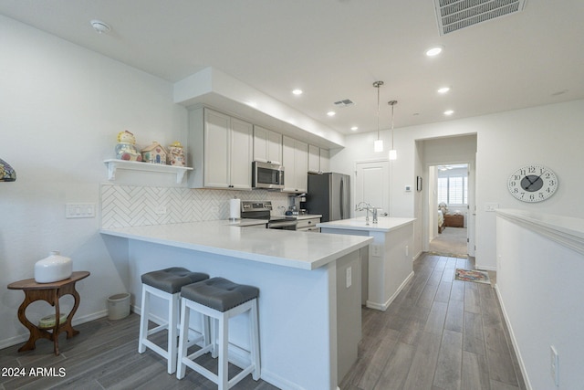 kitchen featuring white cabinets, decorative light fixtures, appliances with stainless steel finishes, dark wood-type flooring, and tasteful backsplash