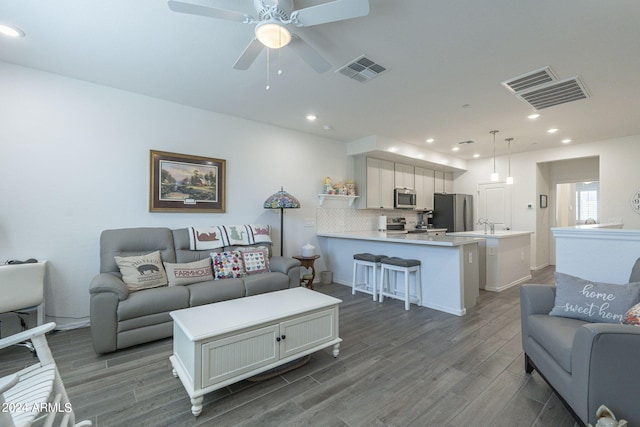 living room featuring wood-type flooring, sink, and ceiling fan