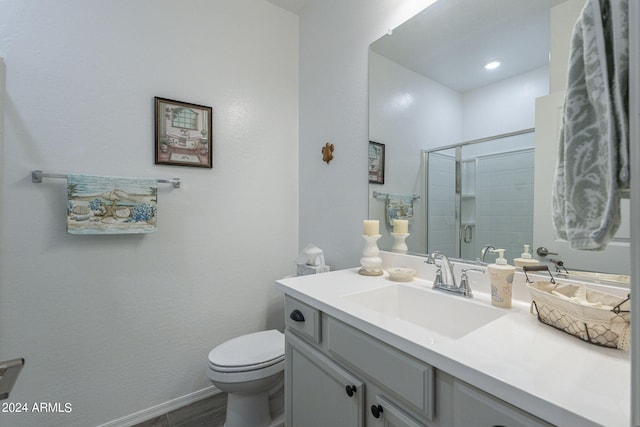 bathroom featuring vanity, toilet, and a shower with door