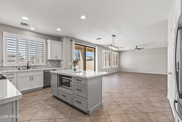 kitchen featuring a wealth of natural light, visible vents, a ceiling fan, tasteful backsplash, and stainless steel appliances