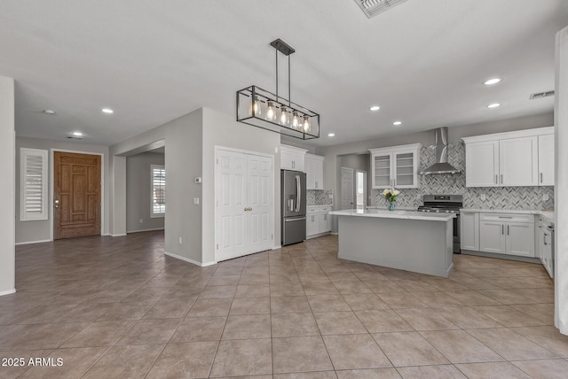 kitchen with visible vents, stainless steel appliances, light countertops, wall chimney exhaust hood, and backsplash