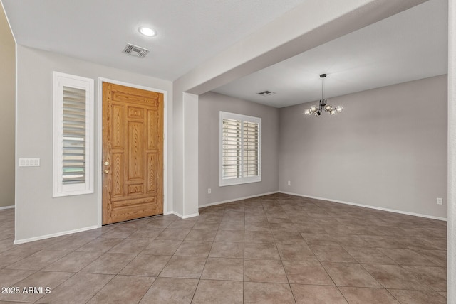 tiled entryway with an inviting chandelier, baseboards, and visible vents