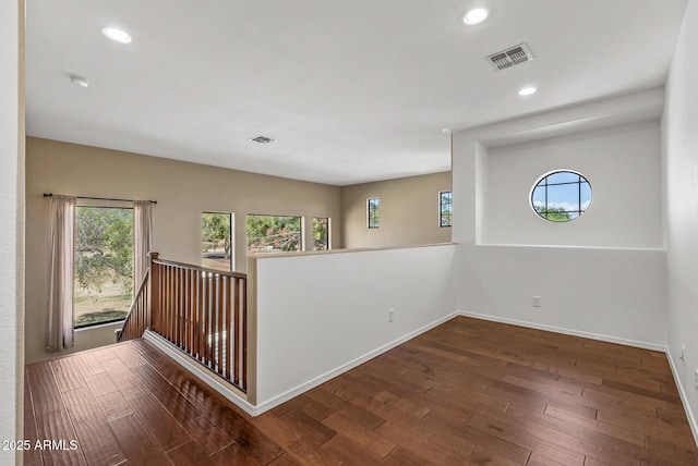 empty room with wood finished floors, visible vents, and a wealth of natural light