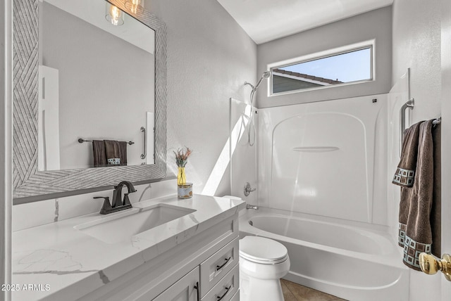 full bath featuring toilet, bathtub / shower combination, vanity, and a textured wall