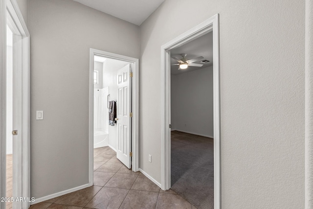 hallway featuring tile patterned floors and baseboards