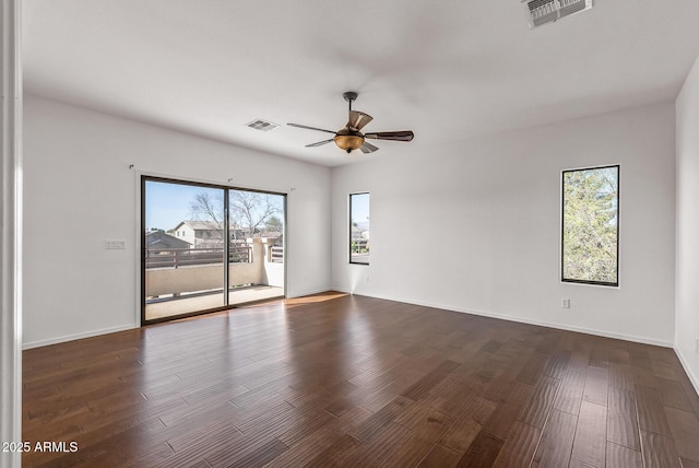 empty room with visible vents, a ceiling fan, and dark wood-style flooring