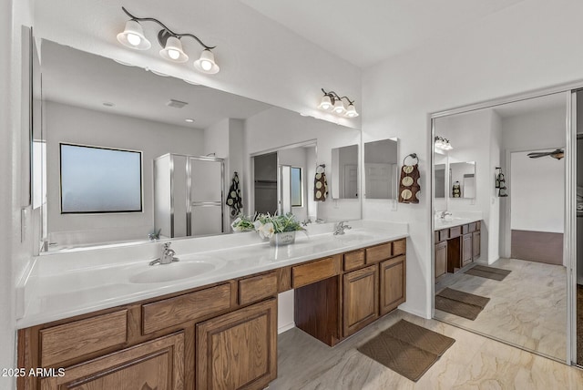 full bathroom featuring double vanity, a stall shower, a ceiling fan, and a sink