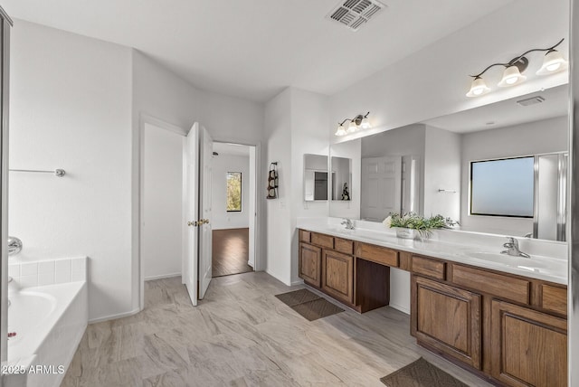 bathroom with double vanity, a garden tub, visible vents, and a sink