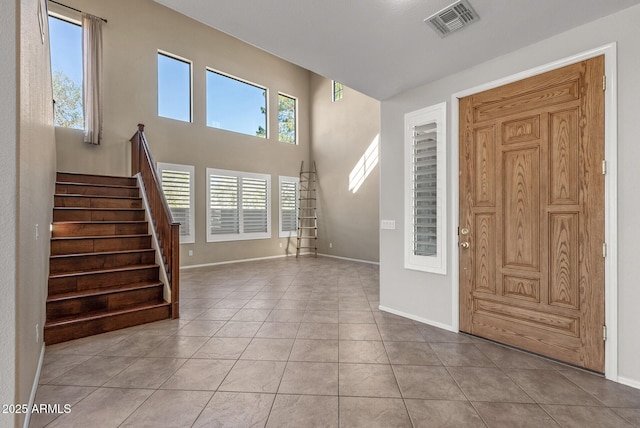 entrance foyer featuring light tile patterned floors, visible vents, stairs, and baseboards