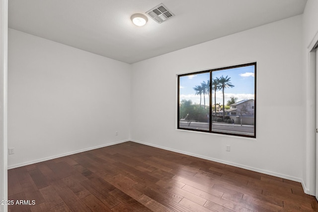 spare room featuring dark wood-type flooring, baseboards, and visible vents