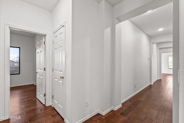 hallway featuring dark wood finished floors and baseboards