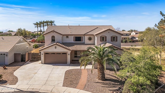 mediterranean / spanish house featuring concrete driveway, fence, a tile roof, and stucco siding