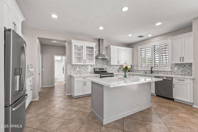 kitchen with stainless steel appliances, wall chimney exhaust hood, and white cabinets