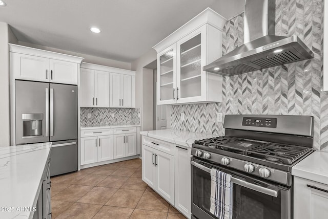 kitchen with white cabinets, appliances with stainless steel finishes, and wall chimney range hood