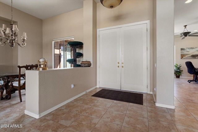 tiled entrance foyer with ceiling fan with notable chandelier