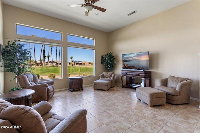 living room with a towering ceiling, ceiling fan, and light tile patterned floors