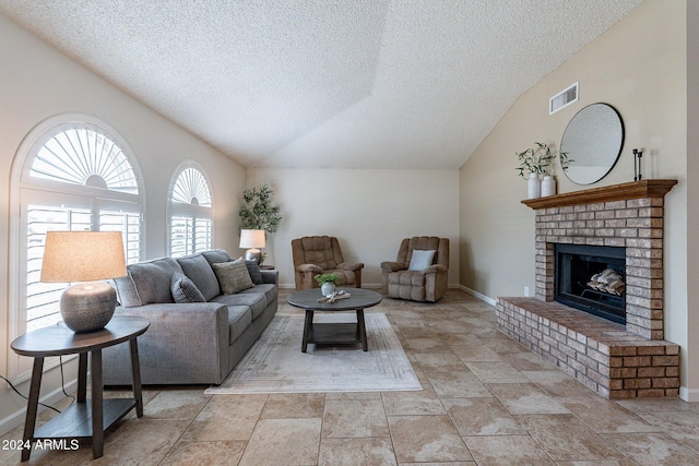 living room featuring lofted ceiling, a textured ceiling, and a brick fireplace