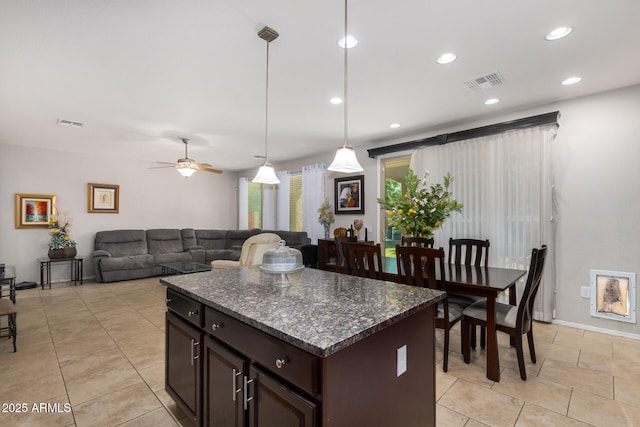 kitchen featuring decorative light fixtures, dark stone countertops, ceiling fan, light tile patterned floors, and dark brown cabinets