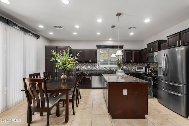 kitchen with decorative light fixtures, tasteful backsplash, a center island, appliances with stainless steel finishes, and dark stone counters