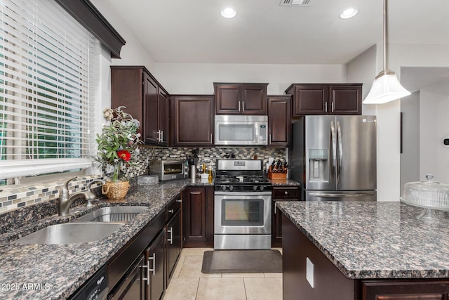 kitchen with dark stone countertops, sink, hanging light fixtures, stainless steel appliances, and dark brown cabinets