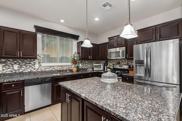 kitchen with decorative backsplash, dark brown cabinets, pendant lighting, and stainless steel appliances