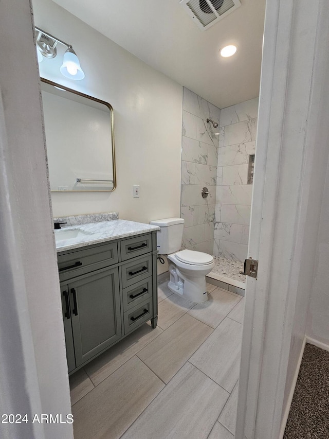 bathroom with vanity, toilet, and tiled shower