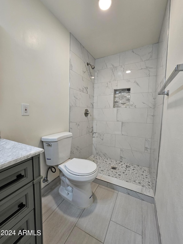 bathroom with vanity, a tile shower, and toilet