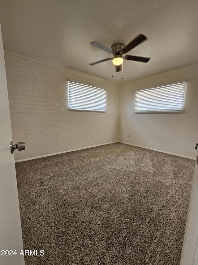 empty room featuring brick wall, carpet, and ceiling fan