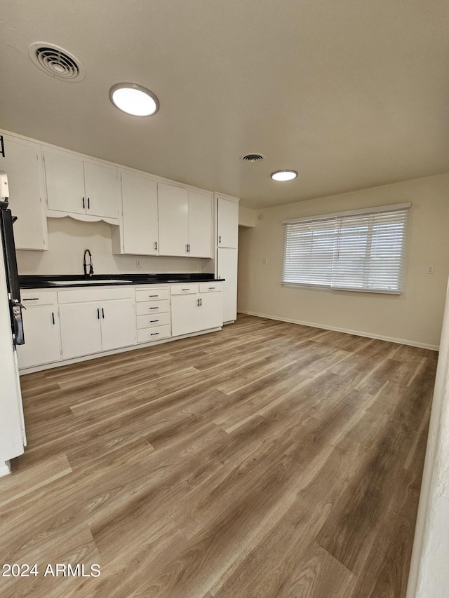 kitchen with white cabinetry, sink, and light hardwood / wood-style flooring