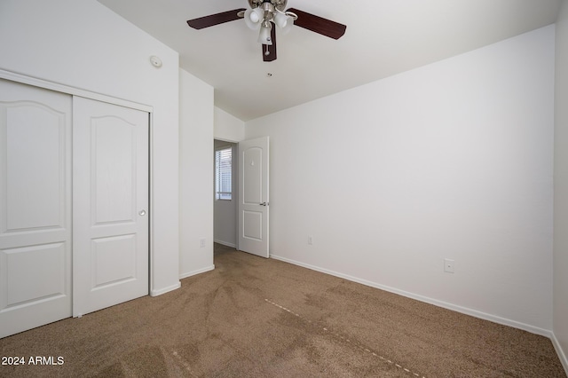 unfurnished bedroom with carpet, a closet, baseboards, ceiling fan, and vaulted ceiling