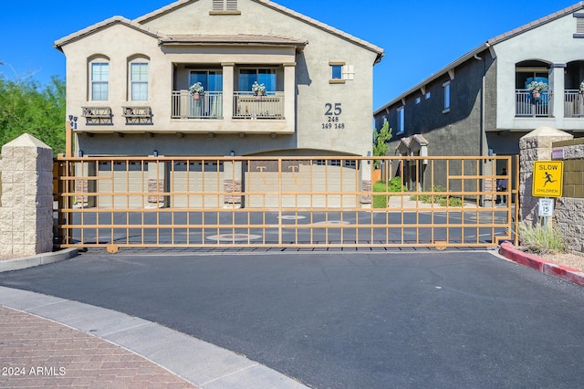 view of front of property featuring a gate, fence, stucco siding, and a balcony