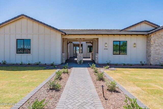 6926 N 177th Pl, Waddell, AZ 85355 - view of front of home featuring board and batten siding, a tiled roof, a front lawn, and stone siding