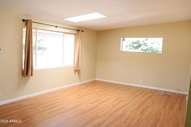 spare room with light wood-type flooring, plenty of natural light, and baseboards