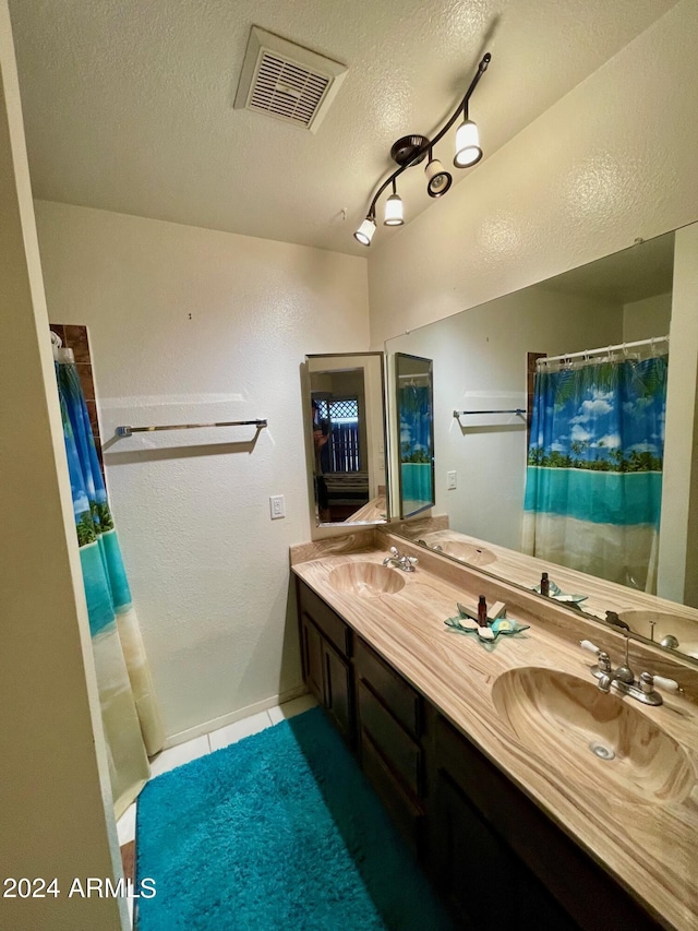 bathroom with a textured ceiling, vanity, and tile patterned floors