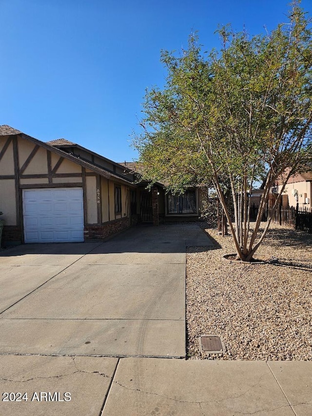 view of front of property featuring concrete driveway, stucco siding, a garage, and fence