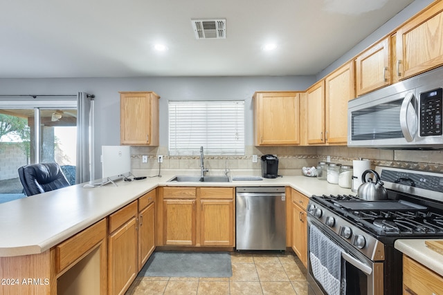 kitchen with backsplash, sink, light tile patterned floors, kitchen peninsula, and stainless steel appliances