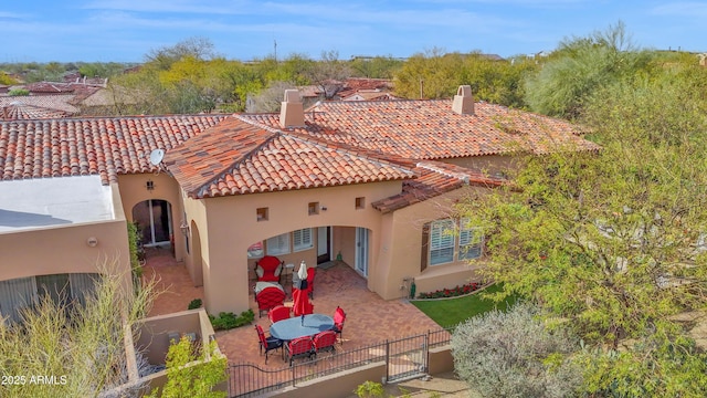 rear view of house featuring fence, a tile roof, a gate, stucco siding, and a patio area