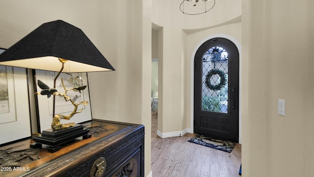 entrance foyer featuring a wealth of natural light, arched walkways, baseboards, and wood finished floors