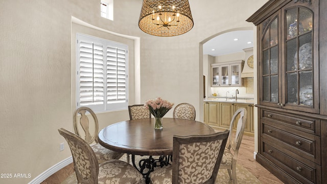 dining space with a notable chandelier, indoor wet bar, arched walkways, and baseboards