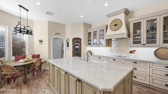 kitchen featuring arched walkways, black electric cooktop, a sink, visible vents, and decorative backsplash