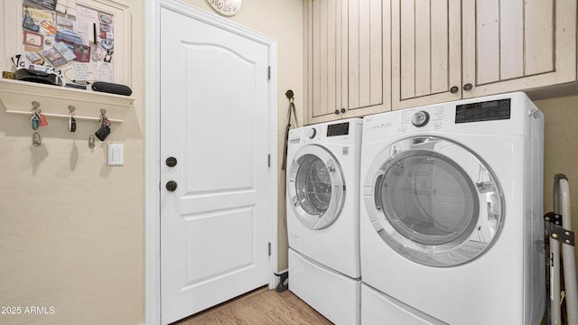 laundry area featuring light wood-type flooring, cabinet space, and washing machine and clothes dryer