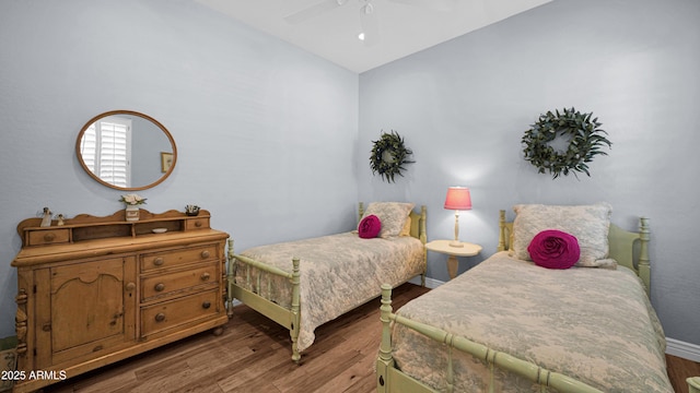 bedroom with a ceiling fan, lofted ceiling, baseboards, and wood finished floors