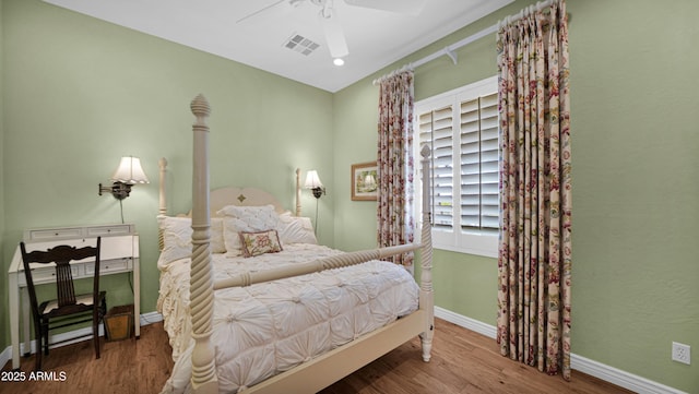 bedroom featuring ceiling fan, wood finished floors, visible vents, and baseboards